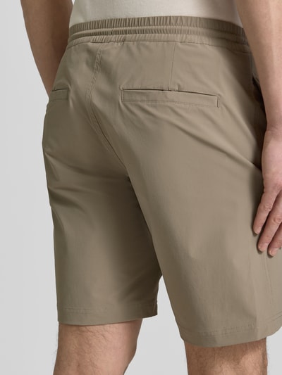 Männermodel trägt Straight Fit Shorts mit Eingrifftaschen Modell 'Drift' von SCANDINAVIAN EDITION in Beige, Ganzkörperansicht Rückansicht.