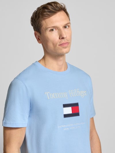 Męski model nosi Regular Fit T-Shirt aus reiner Baumwolle von Tommy Hilfiger, efekt: jednolity kolor, z napisem z logo, wyhaftowane logo, okrągły dekolt, krótki rękaw, dżersej, bawełna, całkowite ujęcie przodu.