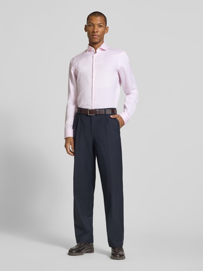 Männermodel trägt Slim Fit Businesshemd mit extra langem Arm von Jake*s, hellrosa, glatte Textur, Ganzkörperansicht von vorne.