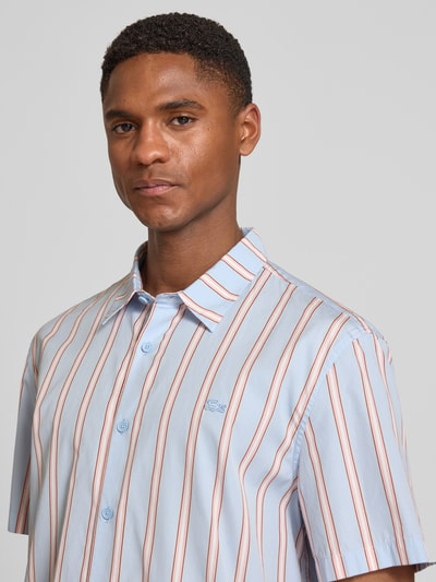 Męski model nosi Regular Fit Freizeithemd aus reiner Baumwolle od Lacoste, popelina, wielokolorowe paski, krótki rękaw, zbliżenie na górną część ciała