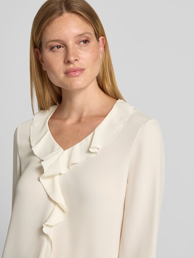 Kobiece model prezentuje Relaxed Fit Bluse mit Rüschenbesatz od Marc Cain, obszycie falbanami, dekolt w serek, z długim rękawem, Długość tyłu w rozmiarze 36: 58 cm, Długość rękawów w rozmiarze 36: 61 cm, jasny kolor, miękka faktura, Nahaufnahme górnej części ciała.