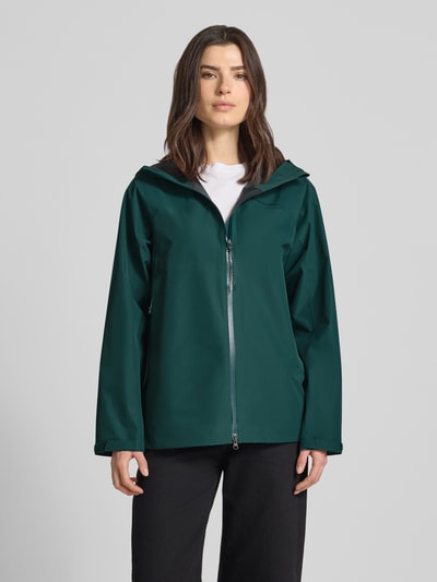 Frauenmodel trägt Regular Fit Jacke mit Logo-Print Modell 'Treeline' von PEAK PERFORMANCE, grün, mit Stehkragen und Kapuze, Rückenlänge 71 cm, Schulterbreite 44 cm, Brustweite 53 cm, Ärmellänge 55 cm. Ganzkörperansicht von vorne