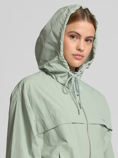 Frauenmodel trägt Regular Fit Jacke mit Logo-Stitching von Lala Berlin in Mint mit Kapuze, Tunnelzug, Eingrifftaschen, Reißverschluss, Nahaufnahme Oberkörper. Rückenlänge bei Größe S: 53 cm, Brustweite: 60 cm, Ärmellänge: 59 cm.