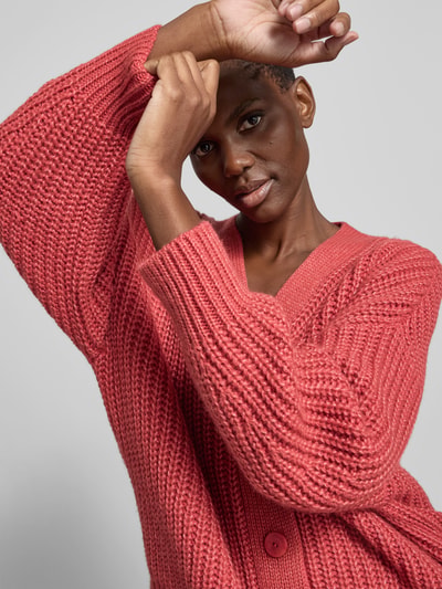 Frauenmodel trägt Oversized Wolljacke mit Kaschmir-Anteil von Joseph in Strick-Optik und gerippten Abschlüssen, Nahaufnahme Oberkörper. Rückenlänge bei Größe S: 65 cm, Woll-Kaschmir-Seide-Mix, durchgehende Knopfleiste.