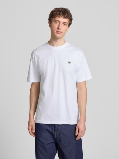 Männermodel trägt Relaxed Fit T-Shirt aus reiner Baumwolle Modell 'FRED' von Only & Sons, unifarben weiß, kurzarm, Rundhals, Jersey, Motiv-Stitching, Label Patch, Ganzkörperansicht von vorne.