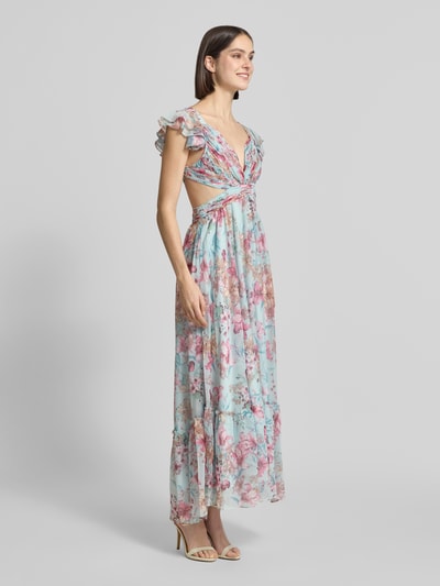 Modelka nosi Regular Fit Maxikleid mit floralem Allover-Print von ADLYSH, niebieskie i różowe kwiaty, wycięcie, falbany, wiązanie, tkanina z fałdami, tkanina o delikatnej fakturze, długość tyłu w rozmiarze S: 116 cm, szerokość w rozmiarze S: 34 cm, widok całej sylwetki z przodu.