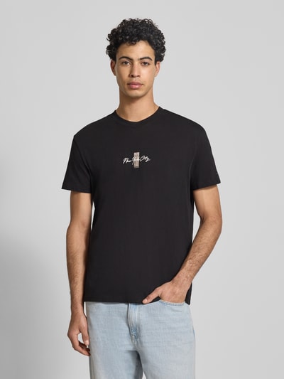 Männermodel trägt Regular Fit T-Shirt aus reiner Baumwolle Modell 'SIGN BLOCK' von Tommy Jeans, Optik: Unifarben, Kurzarmpassform, Schriftzug-Stitching, Label Print, Rücken-Print, Rundhals, Ganzkörperansicht von vorne.