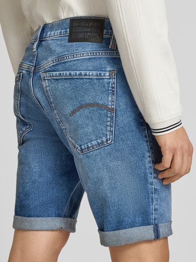 Männermodel trägt Jeansshorts mit Umschlag Modell 'Mosa' von G-Star Raw im Used-Look, blauer Baumwoll-Elasthan-Mix, Ganzkörperansicht Rückansicht