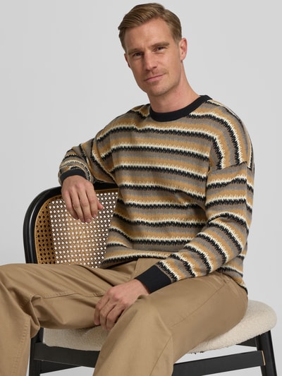 Männermodel trägt Strickpullover mit Rundhalsausschnitt Modell 'Neelio' von Drykorn im Baumwoll-Woll-Mix, Relaxed-Fit, Ganzkörperansicht von vorne.