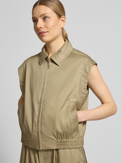 Frauenmodel trägt Weste aus Lyocell-Mix mit Reißverschluss Modell 'Kendall Billie' von MOS MOSH in Beige, glatte Textur, Nahaufnahme Oberkörper. Regular Fit, Umlegekragen, Baumwoll-Anteil, sichtbare Eingrifftaschen, Rückenlänge 53 cm, Schulterbreite 50 cm, Brustweite 45 cm.