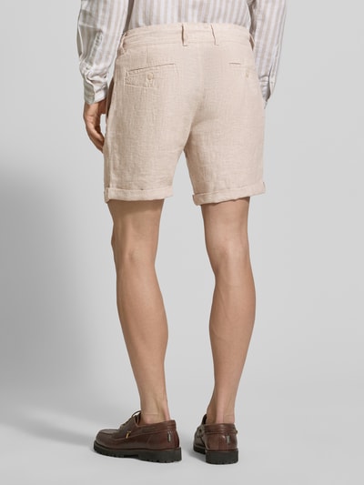 Męski model nosi Leinenshorts mit Bindegürtel und Gesäßtaschen von MCNEAL, len, krój straight fit, jasny beż, tekstura lniana, guziki, zakładka, logo z tyłu, szerokość w rozmiarze M: 45 cm, długość wewnętrzna nogawki: 16 cm, widok całej sylwetki z tyłu.