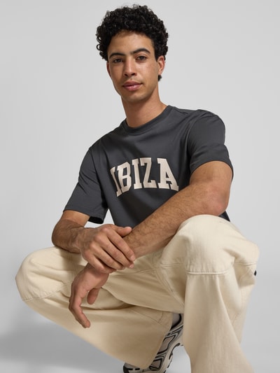Männermodel trägt Relaxed Fit T-Shirt aus reiner Baumwolle Modell 'RICO' von Only & Sons, unifarben mit Motiv-Print, Rundhals, Jersey, Nahaufnahme Oberkörper.