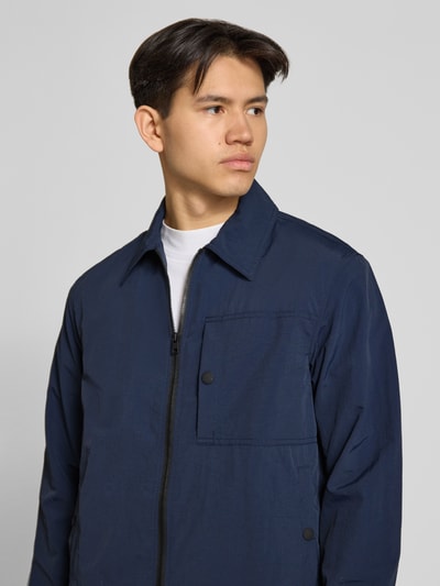 Männermodel trägt Regular Fit Blouson mit Umlegekragen von Marc O'Polo Denim, look: effen, regular fit pasvorm, platte kraag, ritssluiting, labelapplicatie, lange mouw met mouwboord en drukknoop, waterafstotend, zij-steekzakken met drukknoop, borstzak met drukknoop, nahaufnahme bovenlichaam.