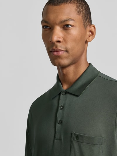 Mannenmodel draagt Regular Fit Poloshirt aus Baumwoll-Mix van RAGMAN in donkergroen met borstzak, katoenmix, regular fit, langärmelig design, elastische boorden, ruglengte maat M 70 cm, Nahaufnahme bovenlichaam.