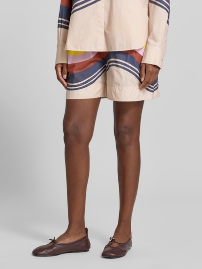 Frauenmodel trägt Regular Fit Chinoshorts aus reiner Baumwolle von Essentiel Antwerp mit abstraktem Farbdesign, Nahaufnahme Beine.