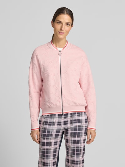 Frauenmodel trägt Regular Fit Strickjacke aus Viskose-Mix von Marc Cain, rosa mit Kontraststreifen, Stehkragen, Nahaufnahme Oberkörper.