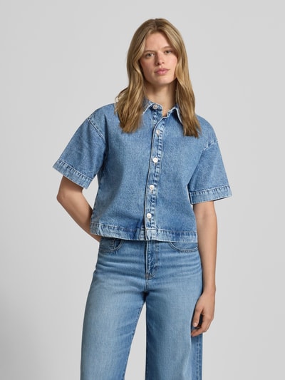 Frauenmodel trägt Loose Fit Jeansbluse aus reiner Baumwolle Modell 'SKY' von Pieces, Denimoptik, kurzarm, einreihige Knopfleiste, Ganzkörperansicht von vorne.