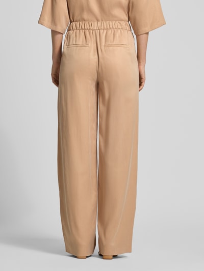 Frauenmodel trägt Wide Fit Stoffhose mit elastischem Bund Modell 'Consider' von Drykorn in Beige, Cupro-Mix, Ganzkörperansicht Rückansicht.
