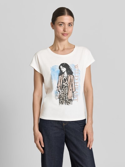 Frauenmodel trägt Damen T-Shirt mit Motiv-Print von Christian Berg Woman, Baumwoll-Viskose-Mix, Regular-Fit, Rundhalsausschnitt, Rückenlänge 57 cm bei Größe S, Weiß mit farbigem Print, Ganzkörperansicht von vorne.