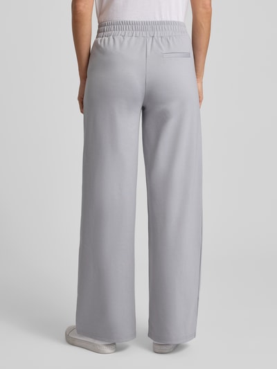Vrouwenmodel draagt Wide Fit Stoffhose met Viskose-Anteil Modell 'Kate' van ICHI in lichtgrijs, elastische tailleband, rechte pijpen, geheelbeeld van achteren.