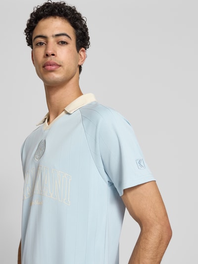 Männermodel trägt Regular Fit T-Shirt mit Umlegekragen Modell 'Heritage' von KARL KANI, Logo-Stitching, hellblau, Nahaufnahme Oberkörper. Rückenlänge bei Größe M: 70 cm, Herren T-Shirt.