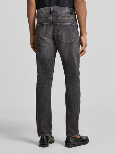 Männermodel trägt Slim Fit Jeans aus Stretch-Denim Modell 'DELAWARE' von BOSS in grauer Denim-Optik, 5-Pocket-Design, Ganzkörperansicht Rückansicht