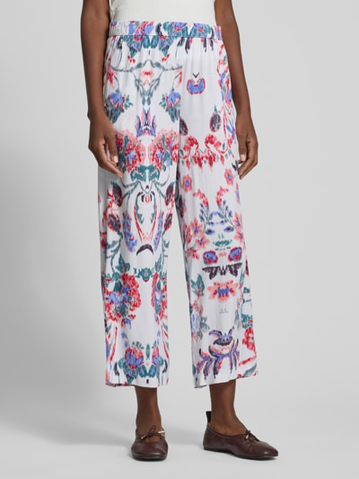 Frauenmodel trägt Culotte aus Viskose mit elastischem Bund von Christian Berg Woman, weiß mit buntem Allover-Muster, Loose Fit, Ganzkörperansicht von vorne.