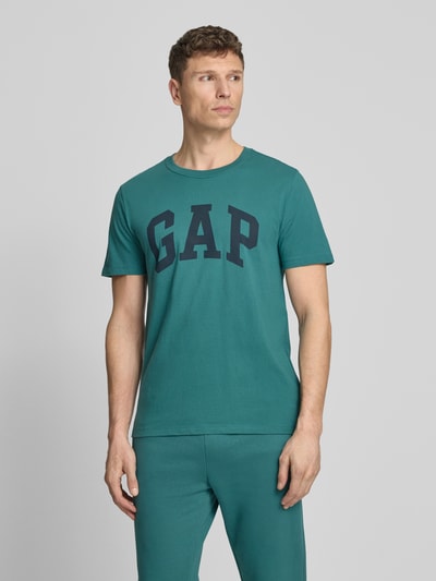 Männermodel trägt T-Shirt mit Logo und Rundhalsausschnitt von GAP in Grün, Reine Baumwolle, Regular-Fit, Logo, Rückenlänge 72 cm, Ganzkörperansicht von vorne