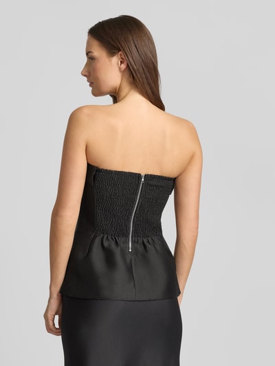 Kobiece modelka nosi Top aus Satin im Ärmellosen Design Modell 'Taleen' od Neo Noir, satyna, czarny kolor, dopasowany krój, widok z tyłu, zdjęcie całopostaciowe.
