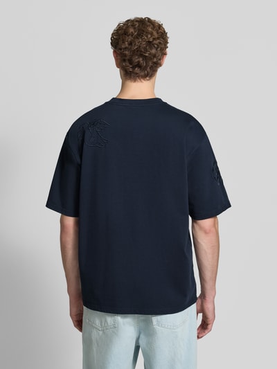 Männermodel trägt T-Shirt mit Stitchings und Rundhalsausschnitt von Scotch & Soda in Dunkelblau, reine Baumwolle, Relaxed Fit, Ganzkörperansicht Rückansicht.
