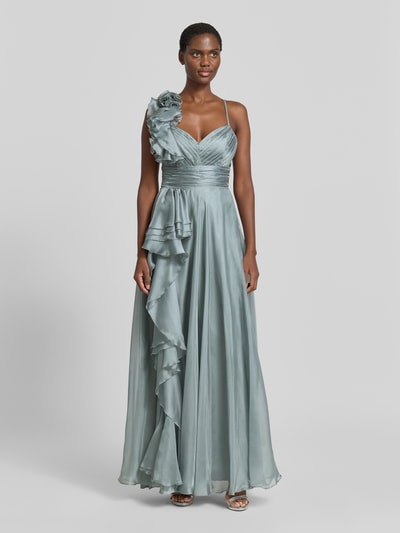 Modelka nosi Abendkleid mit Volants und Herz-Ausschnitt od V.M., satynowa tkanina, A-linia, maxi, ramiączka krzyżowane z tyłu, zapięcie na zamek i haftkę z tyłu, długość pleców w rozmiarze 36: 122 cm, szerokość w rozmiarze 36: 32 cm, kolor srebrnoszary, gładka faktura, falbany, widok całej sylwetki z przodu.
