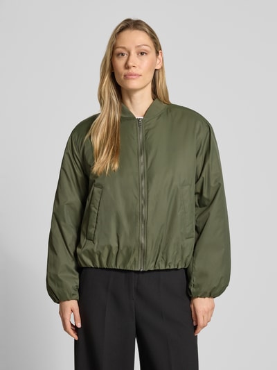 Frauenmodel trägt olivgrüne Bomberjacke mit Reißverschluss, Stehkragen, Eingrifftaschen, Lockerer-Schnitt Modell 'Michi-M' von mbyM, Ganzkörperansicht von vorne. Rückenlänge 56 cm, Schulterbreite 50 cm, Brustweite 58 cm, Ärmellänge 58 cm, Größe S.