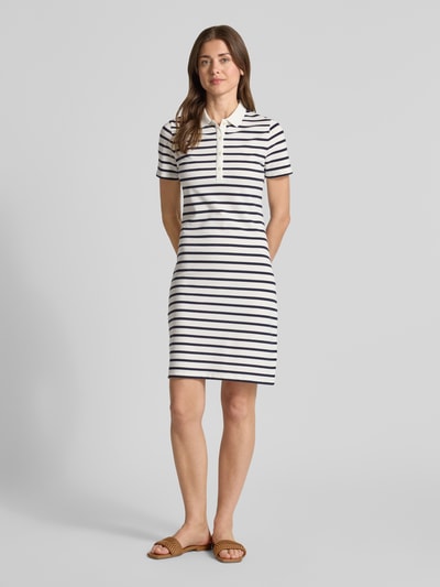 Frauenmodel trägt Knielanges Polokleid mit kurzer Knopfleiste von Gant aus Baumwoll-Mix mit Stretch-Anteil, Körpernaher-Schnitt, Knielänge, Polokragen, kurze Knopfleiste, Rückenlänge bei Größe S: 88 cm, Brustweite bei Größe S: 42 cm, Ärmellänge bei Größe S: 19 cm, weiß mit dunkelblauen Querstreifen, glatte Struktur, Ganzkörperansicht von vorne.