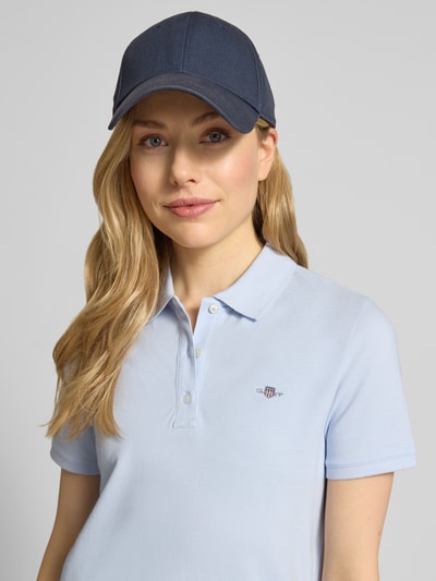 Frauenmodel trägt Poloshirt mit Logo-Stitching und Polokragen von Gant aus reiner Baumwolle im Regular-Fit, hellblau, Nahaufnahme Oberkörper.