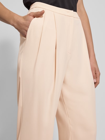 Frauenmodel trägt Stoffhose mit Bundfalten von Emporio Armani in Beige, lockerer Schnitt, französische Eingrifftaschen, Nahaufnahme Oberkörper.