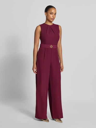 Frauenmodel trägt Jumpsuit mit Stoffgürtel von Rinascimento in Dunkelrot, Material-Mix, taillierte Passform, Ganzkörperansicht von vorne.