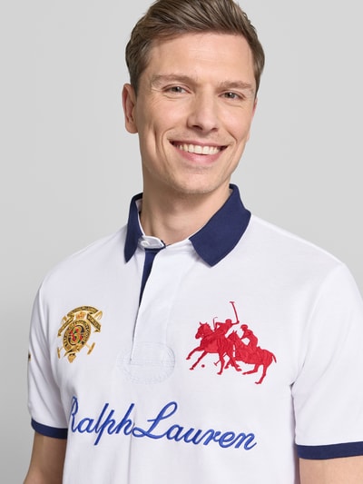 Mężczyzna model nosi Regular Fit Poloshirt aus reiner Baumwolle von Polo Ralph Lauren, białe, niebieski kołnierzyk, haft logo, krój regular fit, bawełna, zbliżenie na górną część ciała.