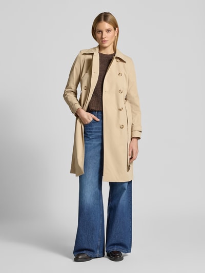 Frauenmodel trägt Trenchcoat mit Ärmelriegeln von Christian Berg Woman Selection in Beige, Doppelknopfleiste, Taillengürtel, Ganzkörperansicht von vorne.