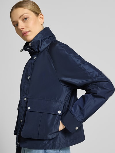 Modelka kobieca nosi Jacke mit Stehkragen und Pattentaschen od Fuchs Schmitt, kolor granatowy, krój regular fit, stójka, tunel, listwa guzikowa, kieszenie z patką, długość tyłu w rozmiarze 36: 58 cm, szerokość ramion w rozmiarze 36: 41 cm, szerokość klatki piersiowej w rozmiarze 36: 54 cm, długość rękawów w rozmiarze 36: 63 cm, widok z przodu na górną połowę sylwetki