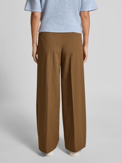 Frauenmodel trägt Wide Fit Stoffhose mit französischen Eingrifftaschen Modell 'SYSTECK' von Mango in Braun, Material-Mix, Ganzkörperansicht Rückansicht.