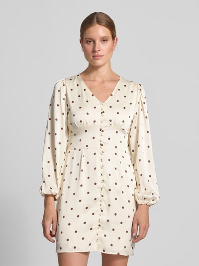 Frauenmodel trägt Slim Fit Minikleid mit durchgängiger Knopfleiste Modell 'Mabel' von Neo Noir in Creme mit braunen Punkten, V-Ausschnitt, langärmelig, elastischer Material-Mix, Ganzkörperansicht von vorne.