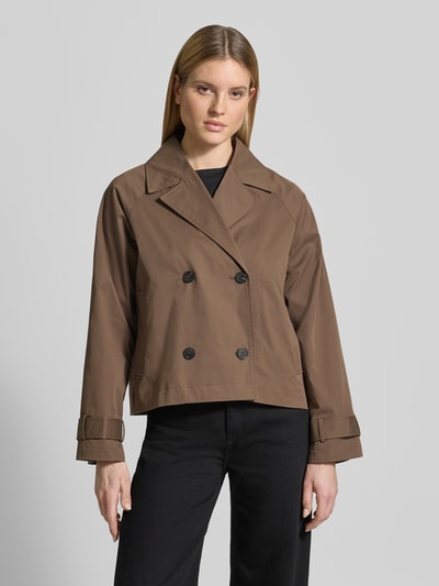 Frauenmodel trägt Regular Fit Trenchcoat-Jacke aus Baumwoll-Mix Modell 'NEW CILO' von Selected Femme in Optik: Unifarben mit Reverskragen, doppelreihiger Knopfleiste, Kellerfalte und Riegel an Langarm; Ganzkörperansicht von vorne.