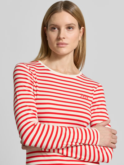 Vrouwenmodel draagt Longsleeve met ronde hals en statement-stitching van comma, viscosemix met stretch, nauwsluitend model, ruglengte maat 36: 52 cm, rood-wit gestreept, textuur glad, nahaufnahme bovenlichaam.