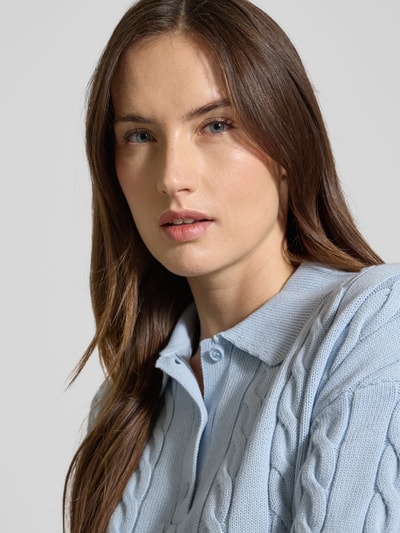 Vrouwenmodel draagt Slim Fit Poloshirt in Strick-Optik van JAKE*S STUDIO WOMAN in lichtblauw katoen met polokraag, ribboorden, pure katoen, korte knoopsluiting, slim fit. Detailopname bovenlichaam.