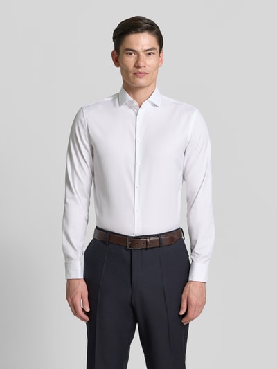 Männermodel trägt Slim Fit Businesshemd aus Twill von Jake*s in Weiß mit Kentkragen und Umschlagmanschette, Ganzkörperansicht von vorne.