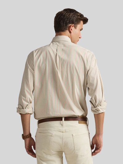 Männermodel trägt Slim Fit Freizeithemd aus Baumwoll-Mix von Polo Ralph Lauren, efekt: wzór w paski na całej powierzchni, wyhaftowane logo, długi rękaw, kołnierzyk typu button down, listwa guzikowa na całej długości, sportowy mankiet, materiał: mieszanka bawełny, flammgarn, kolor beżowy i kremowy, widoczne faktury tkaniny, Ganzkörperansicht Rückansicht.