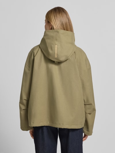 Frauenmodel trägt Jacke mit Kapuze und versiegelten Nähten Modell 'ELLE' von G-LAB in Olivgrün, Lyocell-Mix mit Leinen-Anteil, Gerader-Schnitt, Wasserdicht, Winddicht, Atmungsaktiv, Druckknopfverschluss, Rückansicht Ganzkörperansicht.
