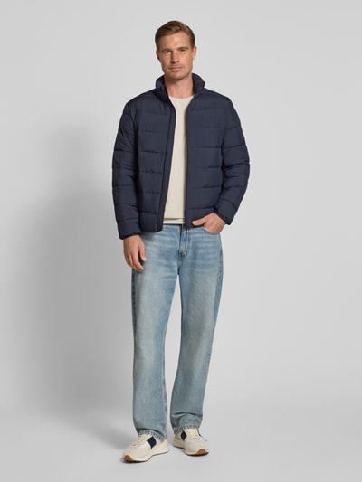 Männermodel trägt Regular Fit Steppjacke mit Stehkragen von Tom Tailor Denim in Dunkelblau, helle Jeans, neutrale Farben, Ganzkörperansicht von vorne, Herren Daunenjacke von Tom Tailor Denim
