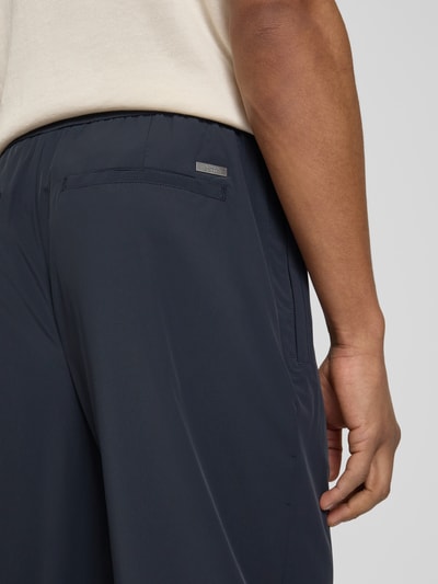 Mężczyzna nosi Hose mit elastischem Bund und Gesäßtaschen od ARMANI EXCHANGE, mieszanka materiałów z dodatkiem streczu, krój relaxed fit, elastyczny pas, kieszenie z tyłu, kolor ciemnogranatowy, Szerokość w rozmiarze 32: 40 cm, długość wewnętrzna nogawki: 79 cm, detal z tyłu, zbliżenie na kieszeń