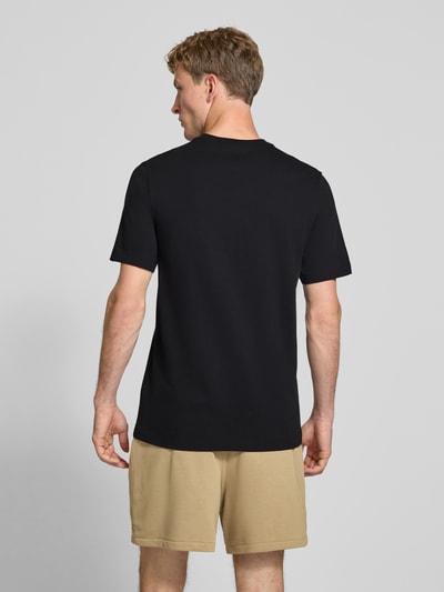 Männermodel trägt Regular Fit T-Shirt aus reiner Baumwolle von Nike in Schwarz, beige Shorts, glatter Stoff, Ganzkörperansicht Rückansicht. Herren T-Shirt von Nike.